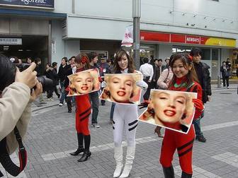 Photomontage dans lequel trois filles asiatiques brandissant des pancartes avec votre photo, dans la rue, avec beaucoup d"impatience.